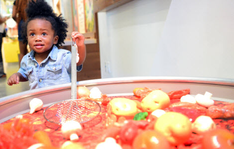 Toddler stirring up the boiling pot of crawfish in the Follow That Food gallery.